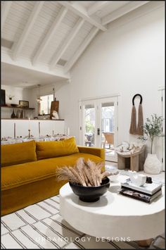 a living room filled with furniture and a white coffee table in front of a yellow couch