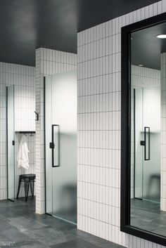 a bathroom with white tiled walls and black trim on the doors, mirrors and stools