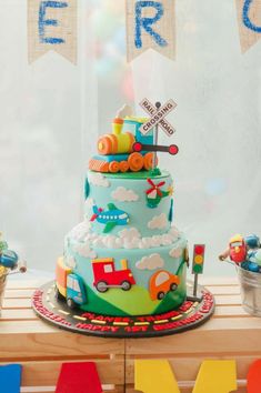 a multi layer cake sitting on top of a wooden table next to colorful letters and bunting