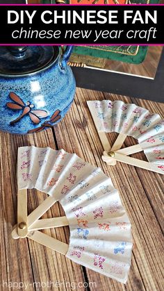 paper fans are sitting on a wooden table next to a teapot and other items