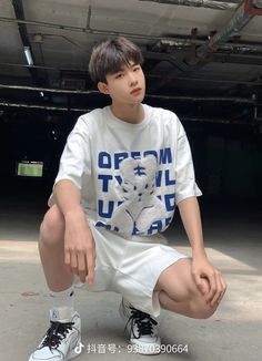 a young man sitting on top of a skateboard wearing white shorts and a t - shirt