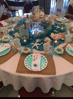 the table is set with dishes and place settings for an ocean themed dinner or bridal party