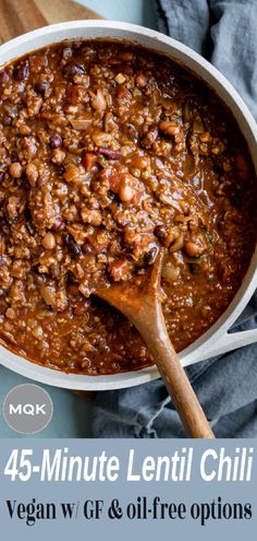 a large pot filled with chili and beans on top of a wooden cutting board next to a