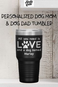 the personalized dog mom and dad tumbler is on display in front of a wooden wall