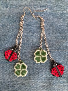 two red and black beads hanging from silver chains on denim material with chain attached to them