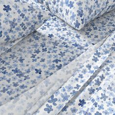 the blue and white bedding is made up with floral print on it's sheets