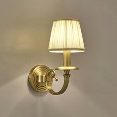 a wall light with a white shade on it and a lamp attached to the side