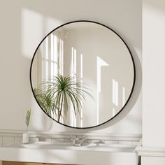 a round mirror hanging on the wall above a sink