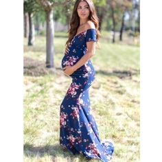 a pregnant woman in a blue floral dress posing for the camera with her hands on her hips