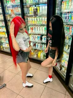 two women standing next to each other in front of a store display filled with drinks