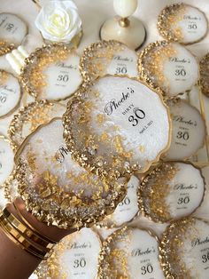 a table topped with lots of cookies covered in gold sprinkles and white frosting