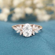 a close up view of a diamond ring on a blue surface with flowers in the background