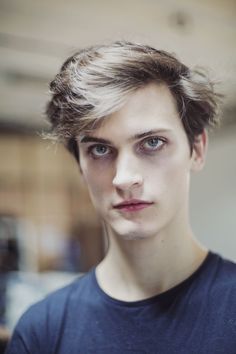 a close up of a person wearing a blue t - shirt and looking at the camera