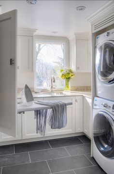 a washer and dryer in a white kitchen with gray tile flooring on the walls