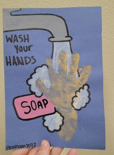 a child's hand holding up a poster with soap on it