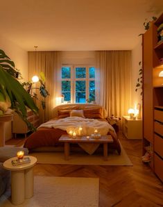 a bed room with a neatly made bed and candles on the table in front of it