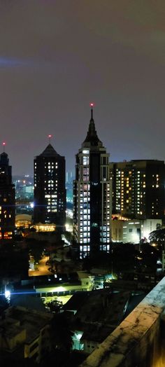 the city skyline is lit up at night with bright lights and skyscrapers in the background