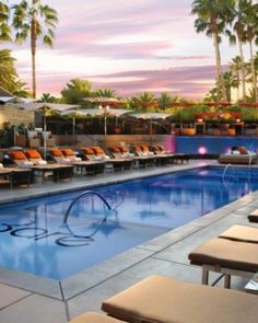 an outdoor swimming pool with lounge chairs and umbrellas