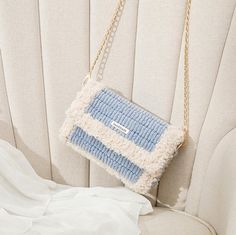 a blue and white purse hanging from the back of a chair with chains attached to it