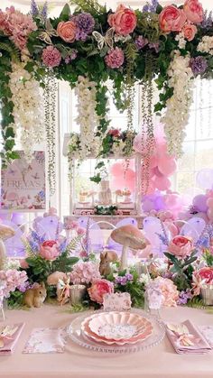 a table topped with lots of pink and white flowers next to a window filled with balloons