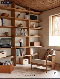 a wooden book shelf filled with books next to a chair and desk in front of a window