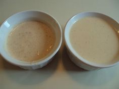 two white bowls filled with soup on top of a table