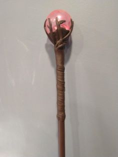 a wooden stick with a pink glass ball on it's end, hanging from the wall