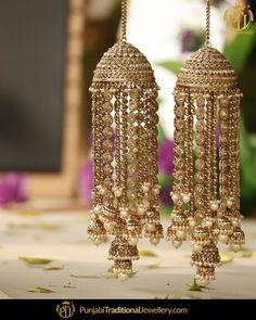 two gold - toned chandeliers with pearls hanging from them on a white tablecloth