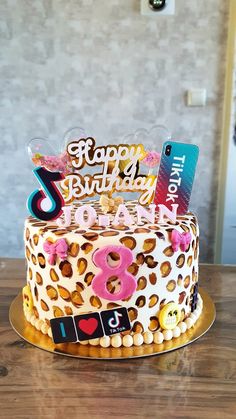 a birthday cake decorated with leopard print and colorful decorations on a wooden table in front of a brick wall