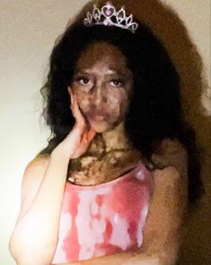 a woman wearing a tiara posing for the camera with her hand on her face