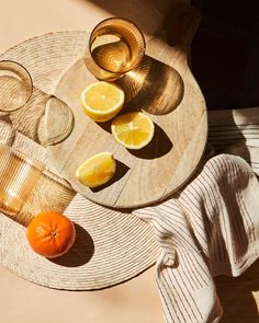 an orange sitting on top of a wooden table next to two glasses and a bowl