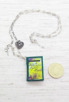 a necklace with a tag attached to it and a coin on the ground next to it