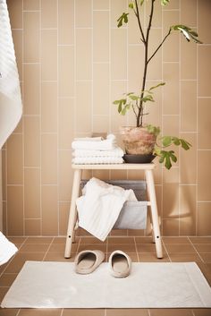 a bathroom with a potted plant and towels on a shelf next to a pair of slippers