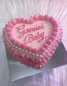 a pink heart shaped cake with the words genni baby on it's side