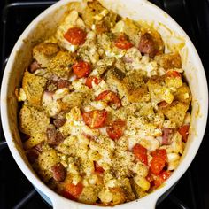 a casserole dish with tomatoes, sausage and cheese in it on the stove