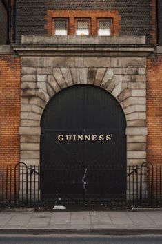 an old building with a black gate and the word guinness on it's door