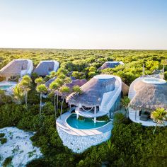 an aerial view of some huts in the middle of trees