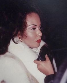 a woman in a fur coat holding a cell phone