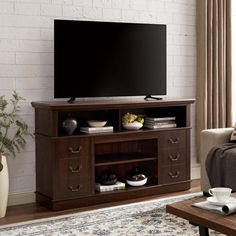 a flat screen tv sitting on top of a wooden entertainment center in a living room