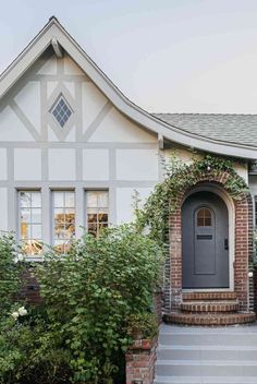 a gray front door on a white house with steps leading up to the entryway