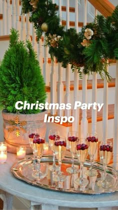 a tray filled with champagne glasses next to a christmas wreath on the bannister