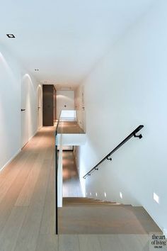 an empty hallway with stairs and railings leading up to the second floor in a modern home