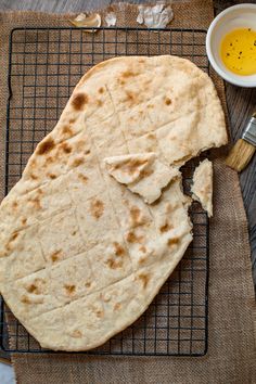 two pita breads on a cooling rack next to a bowl of olive oil