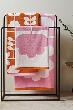 three towels on a rack next to a potted plant