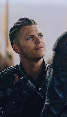 a man with braids looks up into the sky while standing in front of other people