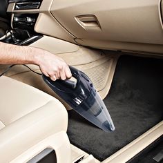 a man is using an iron on the floor in his car while holding it up