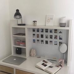 a white desk topped with a laptop computer next to a shelf filled with books and pictures