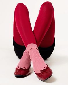 the legs and feet of a woman wearing red stockings with bows on them, sitting in front of a white background