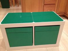 two green lego boxes sitting on top of a kitchen floor next to a countertop