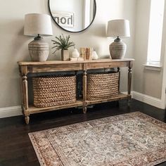 a living room with a rug and two lamps on top of the table next to a mirror